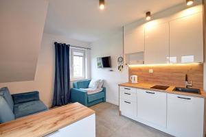a kitchen with a sink and a blue couch at Morski Zakątek Apartamenty in Rowy