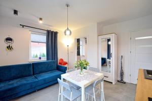 a living room with a blue couch and a table at Morski Zakątek Apartamenty in Rowy