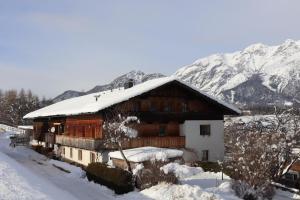 a house covered in snow with mountains in the background at Pechhof in Innsbruck