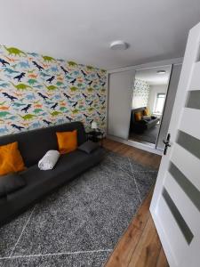 salon z czarną kanapą i kolorową ścianą w obiekcie Orlicka Apartament w mieście Duszniki Zdrój