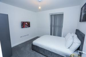 a white bedroom with a bed and a window at LOVELY 2 BED APARTMENT WITH PARKING in Woolwich