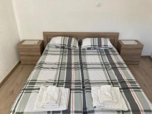 un letto con lenzuola a quadri e asciugamani bianchi di Private Room with lovely yard a Sandanski