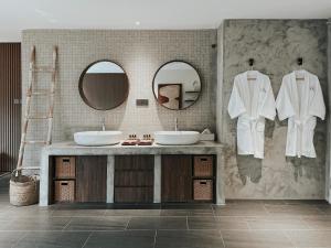 a bathroom with two sinks and two mirrors at The Cara Boutique Hotel in Kota Kinabalu