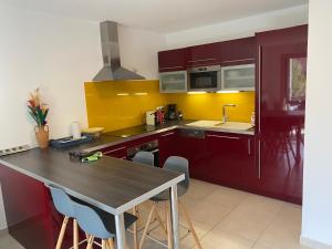 une cuisine avec des placards rouges et une table avec des chaises dans l'établissement Appartement à quelques minutes du lac d’Annecy - Saint-Jorioz, à Saint-Jorioz