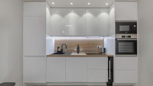 a white kitchen with a sink and a microwave at Apartman Nostra in Zagreb