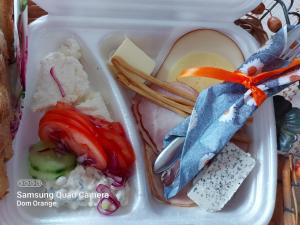 a plastic container filled with food with cheese and vegetables at Dom Gościnny Orange in Wysowa-Zdrój