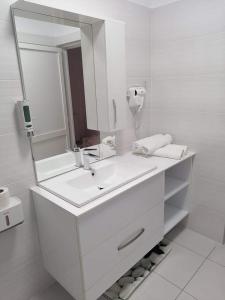 a white bathroom with a sink and a mirror at Happy House in Hunedoara