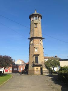 uma torre de tijolos com uma cerca à volta. em Old Lighthouse View penthouse em Harwich