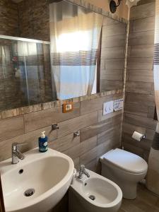 bagno con lavandino, servizi igienici e specchio di CASA DI ALICE A 250 METRI DAL MARE a Noto
