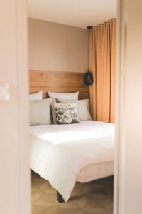 a bedroom with a white bed with a wooden headboard at Chalet Fuusslee in Goebelsmuhle