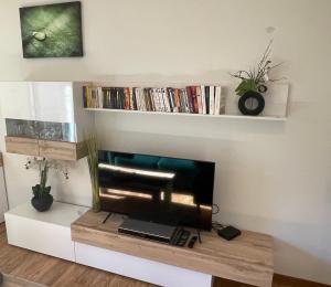 ein Wohnzimmer mit einem Flachbild-TV auf einem Regal in der Unterkunft JARDINS DE RAMEL – APPT 2106*** - CURE/SKI WIFI in Luchon