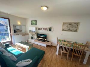 a living room with a green couch and a table at JARDINS DE RAMEL – APPT 2106*** - CURE/SKI WIFI in Luchon