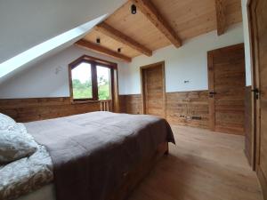 Wilcza Dolina في Sękowa: غرفة نوم بسرير ونافذة وجدران خشبية
