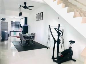 a living room with a table and a treadmill and a kitchen at Chempaka Homestay (Near to UTP UiTM Seri Iskandar) in Seri Iskandar