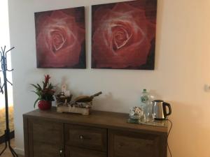 two paintings of roses are hanging above a wooden cabinet at Maison de Campagne in Sarroux