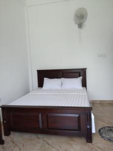 een bed met een houten frame en een wit matras bij Ceylan Star Guest Inn in Wellawaya