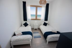 dwa łóżka pojedyncze w pokoju z oknem w obiekcie Sundinia Home, Vista sul Mare w mieście Porto Torres