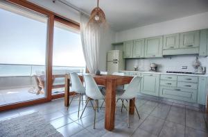 kuchnia z drewnianym stołem i białymi krzesłami w obiekcie Sundinia Home, Vista sul Mare w mieście Porto Torres
