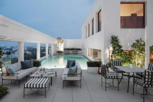 an outdoor patio with a pool and tables and chairs at The Raintree, St. Mary’s Road in Chennai