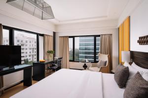 a hotel room with a bed and a desk and windows at The Raintree, St. Mary’s Road in Chennai