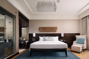 a bedroom with a large bed and a chair at The Raintree, St. Mary’s Road in Chennai