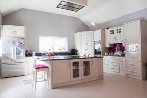 a large kitchen with white cabinets and a kitchen island at Arvalee Retreat With Outdoor HotTub in Omagh