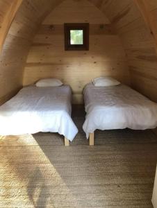 two beds in a wooden cabin with a window at Camping & Glamping Muiñeira in O Grove