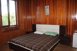 a bedroom with a bed with wooden walls and a window at Hotel Villa Oasis in Kobuleti
