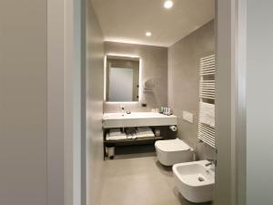 a bathroom with a sink and a toilet and a mirror at Hotel Aquarius Venice - Ascend Collection in Venice