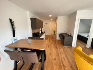 a living room with a wooden table and a kitchen at Neues Traunsee Apartment Altmünster in Altmünster