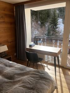 um quarto com uma secretária e uma grande janela em Laax Flims Luxury Large apartment near Rock Resort em Laax-Murschetg