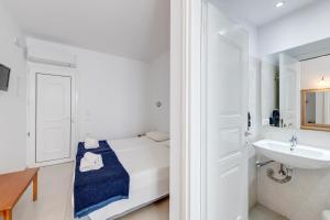 a white bathroom with a bed and a sink at Makis Place in Tourlos