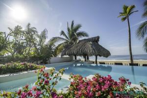 a pool at the beach with palm trees and flowers at Villa Rincon del Mar & Villa Rincon de las Morenas in Coyuca