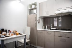 パレルモにあるPalermo al Centro - Appartamento Fiumeのキッチン(白いキャビネット、テーブル、コンロ付)