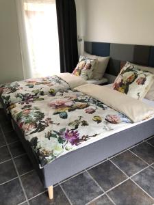 a bed with a floral bedspread on top of it at Fly B&B in Skive