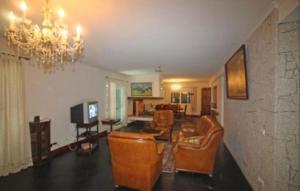 Elle comprend un salon doté d'un mobilier en cuir et d'un lustre. dans l'établissement Casa Ze da Cotta, à Vila Verde