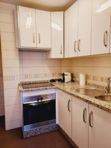 a kitchen with white cabinets and a dishwasher at Apartamento La Muralla in Baena