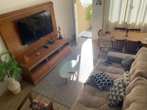 a living room with a couch and a flat screen tv at Lindo Loft completo perto de cachoeira in Guapimirim