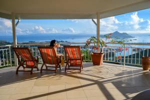 une femme assise sur un balcon donnant sur l'océan dans l'établissement Beau Séjour Hotel, à Victoria