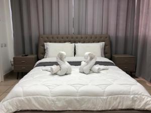 twee knuffeldieren zitten op een bed bij Hotel Room Service in Bat Yam