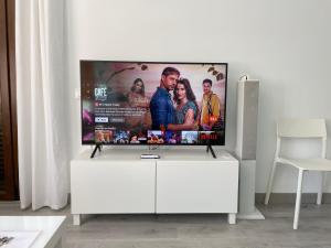 TV de pantalla plana con soporte blanco en la sala de estar en Apartamentos Roquetas Beach, en Roquetas de Mar