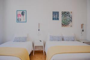 a bedroom with two beds and a painting on the wall at Residencial Avenida in Faro