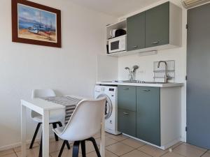 a kitchen with a table and a sink and a microwave at Studio climatisé 1 à 4 personnes vue mer in Le Grau-du-Roi +14 photos