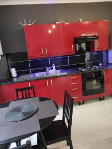 a red kitchen with a table and red cabinets at GO TO LUX Logement Entier [Parking Gratuit] in Algrange