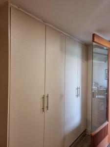 a closet with white cabinets and a glass door at The Polo Residence, Lahore, Near Allama Iqbal International Airport (Apartment) in Lahore