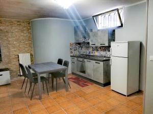 a kitchen with a table and a white refrigerator at La Taverna Appartamento Scala a Chiocciola in Follonica