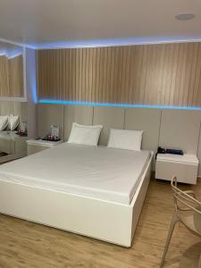 ein großes weißes Bett in einem Zimmer mit Stuhl in der Unterkunft Motel Fascínio (Only Adults) in Cascavel