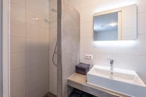 a white bathroom with a sink and a mirror at Bed & Parking Burght van Texel in Den Burg