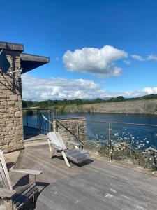 a deck with two chairs and a view of the water at Clearwater - Luxury lakeside house in Borwick