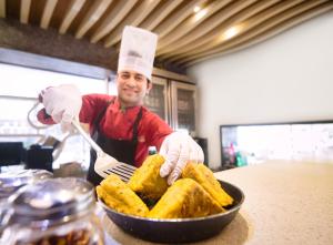 Ein Mann mit Kochmütze bereitet Essen in einer Pfanne zu in der Unterkunft Hotel Oriental Aster - Mumbai International Airport in Mumbai